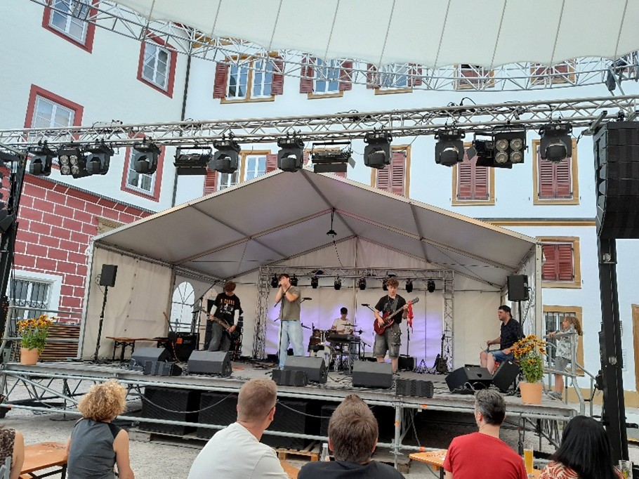 4 Musiker auf Bühne, 2 Gitarristen, 1 Person am Keyboard und eine am Schlagzeug, bühne steht in einem Schlosshof